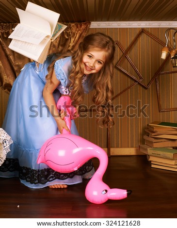Little girl in a blue dress in little room with flamingo