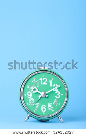 Old green retro clock on blue background with copy-space