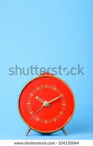 Retro old red clock on blue background with copy space