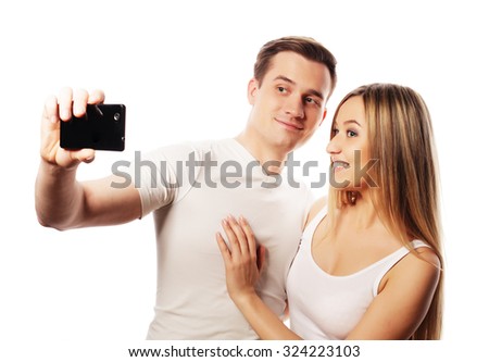 technology, love and friendship concept - smiling couple with smartphone, selfie and fun. Studio shot over white background. 
