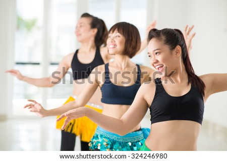 Joyful Asian women performing belly dance in studio Royalty-Free Stock Photo #324246980