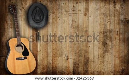 Cowboy hat and guitar against an old barn background.