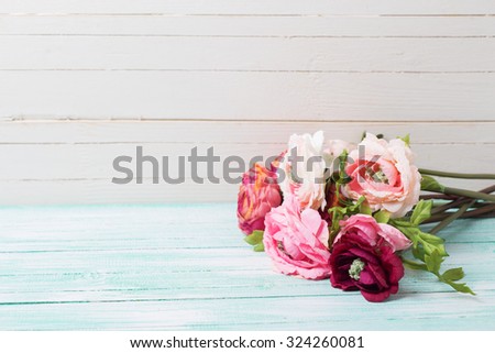 Flowers  on turquoise wooden background against white wall and empty place  for your text. Selective focus.