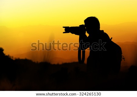 Silhouette of photographer during in sunset with mountains background