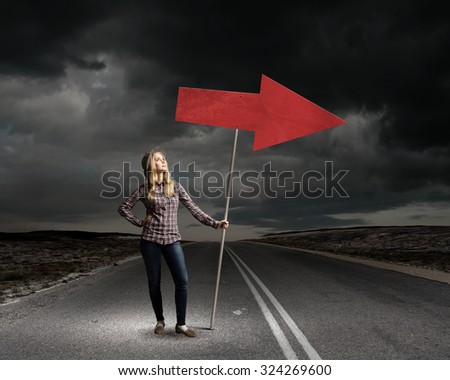 Young girl with arrow signbord in empty room