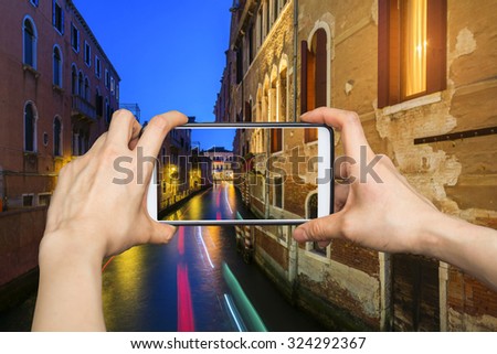 Girl taking pictures on mobile smart phone in Venice, at dusk water canal and traditional colorful houses. Alsace, Italy.