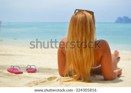 Blond laying on the beach watching the ocean