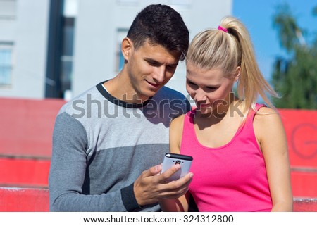 Attractive young couple with smartphone outside