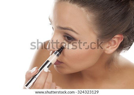 young woman apply concealer under the eye Royalty-Free Stock Photo #324323129