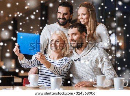 people, leisure, communication, technology and season - happy friends with tablet pc computer taking selfie at winter cafe