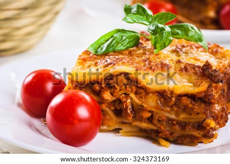Piece of tasty hot lasagna with red wine. Selective focus
