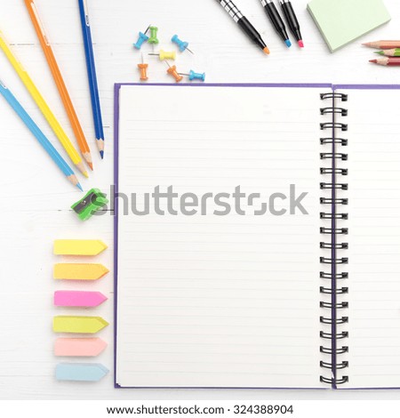 notepad with office supplies on white table view from above