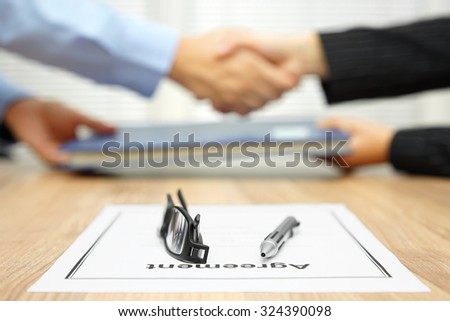 businessman and businesswoman are shaking hands and exchanging folder  after agreement was reached