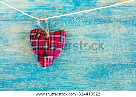 Decorative fabric heart  hanging on the blue wooden background