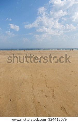 The sandy beach of the Atlantic Ocean. South of France. Basque Country. Hendaye. Blue sky with high clouds and yellow sand. horizon line in the middle. space for inscriptions.