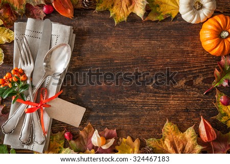 Thanksgiving autumn place setting with cutlery and arrangement of colorful fall leaves