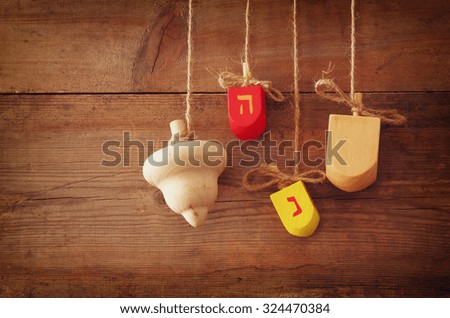 image of jewish holiday Hanukkah with wooden colorful dreidels (spinning top) hanging on a rope over wooden background
