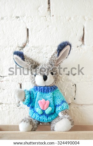 Cute Rabbit Plush Doll Wearing a Blue Sweater on Vintage Brick Wall, for Background, Wallpaper