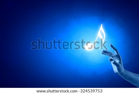Close up of person hand touching music symbol on blue background