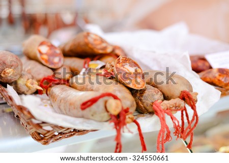 Picture of fresh meat sausages with red strings on tabletop. Spicy delicatessen on blurred market indoor background.