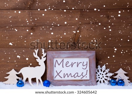 Blue Christmas Decoration On Snow. Christmas Balls, Snowflakes, Reindeer And Christmas Tree. Christmas Card With Picture Frame With English Text Merry Xmas. Rustic, Vintage Brown Wooden Background. 