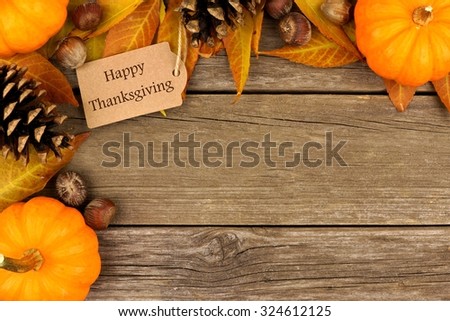 Happy Thanksgiving gift tag with corner border of colorful leaves and pumpkins over a rustic wood background Royalty-Free Stock Photo #324612125