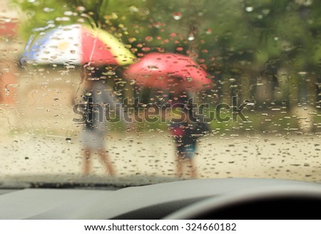 Mother and son with  umbrella walking in the rain after school in blur background
