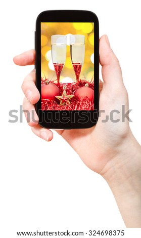 hand holds telephone with Christmas still life on screen isolated on white background