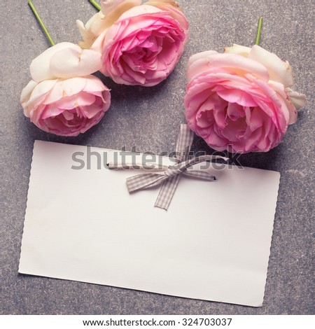 Pink roses  flowers and empty tag for your text on grey background. Selective focus is on tag. Square image.