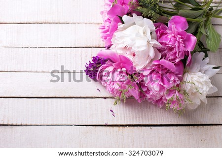 Pink and white peonies flowers on white painted wooden planks. Selective focus. Place for text.