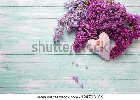 Background  with fresh lilac flowers and textile decorative heart  on turquoise wooden planks. Selective focus. Place for text.
