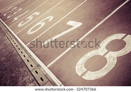 Running track with numbers from 1 to 8. Shot in a unique angle. A gutter along the track. Vintage effect.