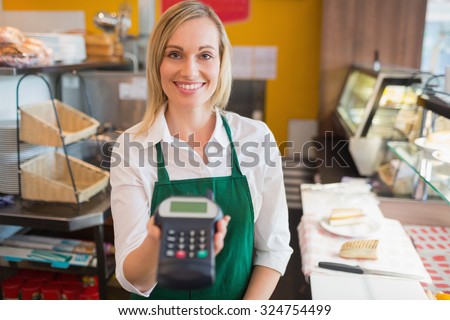 Portrait of happy female shop owner holding credit card reader in bakery