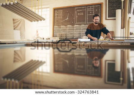 Professional craftsman working with skill and concentration in his naturally lit studio Royalty-Free Stock Photo #324763841