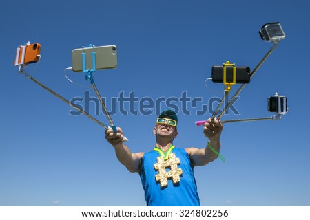 Hashtag gold medal athlete smiling for his many gadgets on selfie sticks as he poses for a picture