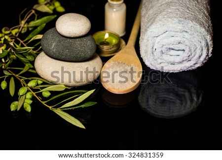 luxury SPA still life with stones, aromatic candles, olives and towel on black background