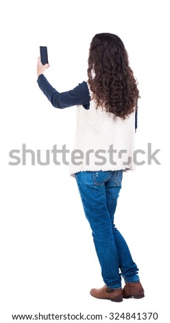 back view of standing young beautiful  woman and using a mobile phone. girl  watching. Rear view people collection.  backside view of person.  Isolated over white background. 