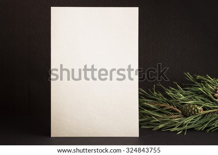 Mockup. Silver card and a sprig of pine trees on a black background.