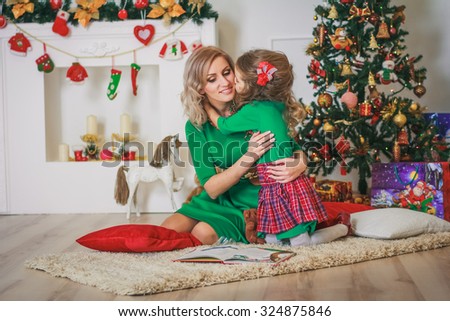 Mother with daughter near the new year tree in studio