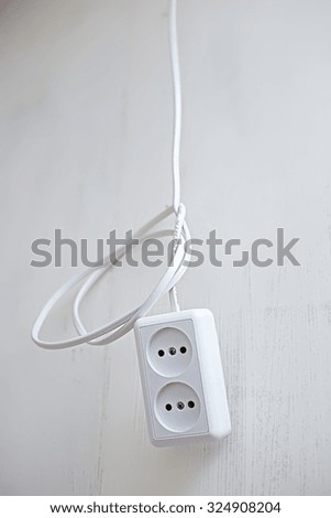 electric socket, knotted hanging on the wire against the backdrop of plasterboard