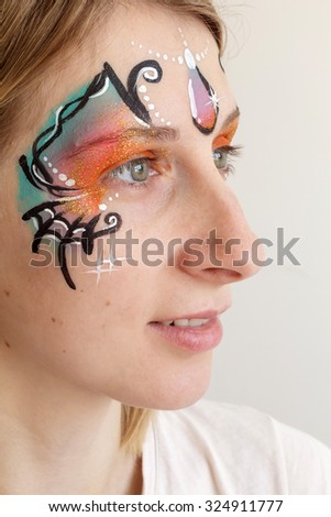 Smiling young blond woman with her face painted with butterfly mask