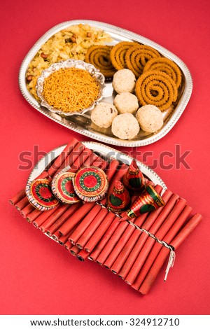 Diwali food /snacks /sweets with fire crackers in silver plate isolated on plain background