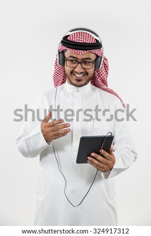Arab man using digital tablet and listening music on headphones