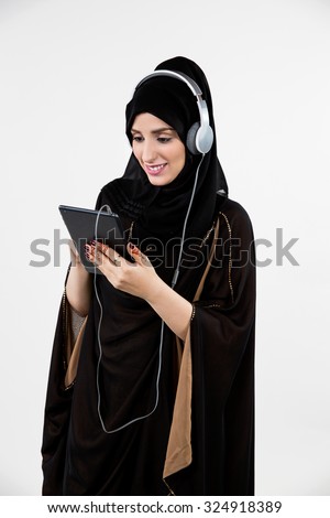 Arab woman using digital tablet with headphones