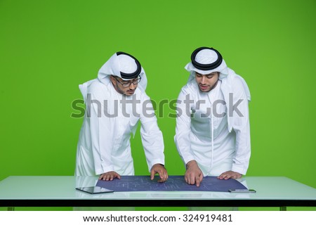 Emirati businessmen discussing over blueprint