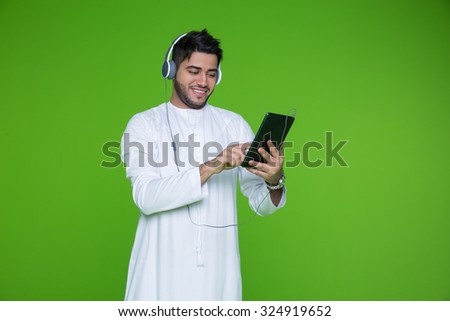 Emirati man using digital tablet and listening music on headphones