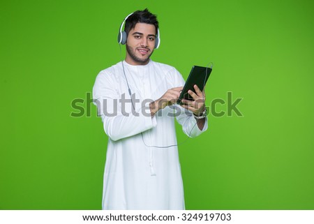 Portrait of Emirati man using digital tablet and listening music on headphones