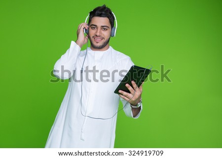 Portrait of Emirati man using digital tablet and listening music on headphones