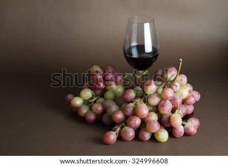 glass of red wine with bunch of pink  grapes