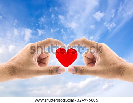 heart in hands on sky background, concept healthcare and valentine's day